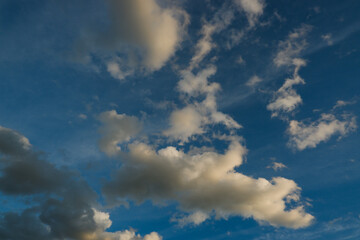 Blue deep sky with a few clouds illuminated by the setting sun.