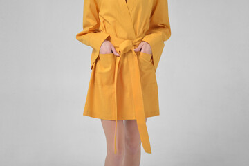 A girl without a face in a yellow haoate stands in the studio on a white background