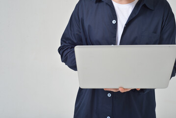 A man without a face on a white background in the studio holds a laptop in his hands works