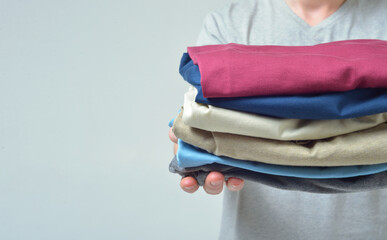 Close-up of a man without a face stretches his arms forward with a stack of clothes
