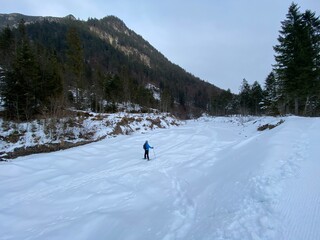 Schneeschuhwandern am Achensee Pertisau im Gerntal Pletzach in der Nähe von Schwaz Innsbruck Tirol Grenze zu Bayern am späten Nachmittag im Winter an einem Wehr im vereisten Bachbett - obrazy, fototapety, plakaty