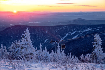 Colorful winter sunset lift ski resort in Sheregesh mountains with clouds forest Russia