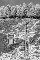 Old chairlift gondola in ski station next to mountain and snowy pine trees