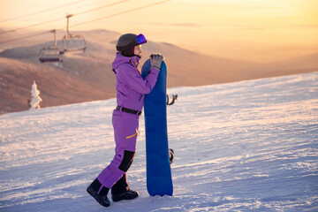 Happy woman snowboarder enjoys Sheregesh ski resort sunset