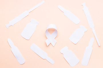 oncology and disease symbol and medical supplies such as vial, syringe made white paper. pink background. above view. medication concept