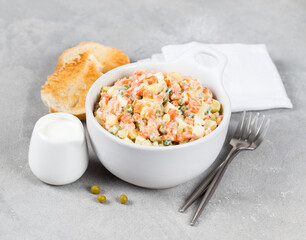 Russian vegetable salad olivier with red fish in a bowl on a light gray background