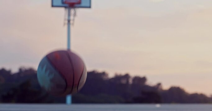 Basketball bouncing on outdoor basketball court at sunrise