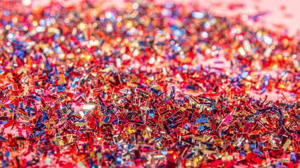 Close-up of a bunch of shiny confetti on pink background. Carnival and party concept. Vertical photography. Copy Space