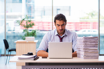 Fototapeta na wymiar Young male employee unhappy with excessive work in the office