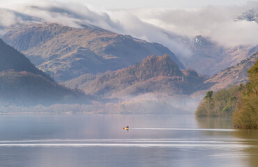 Canoeist paddling across Derwentwater on a beautiful misty morning in the heart of the Lake District, Cumbria