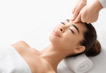 Obraz na płótnie Canvas Attractive young korean woman receiving acupressure head massage in spa salon