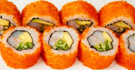 Sushi roll California roll on a white background, ingredients Shrimp, cucumber, avocado, flying fish roe, rice, nori. Traditional Japanese food. For the restaurant menu