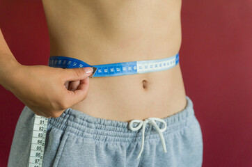 Skinny young woman measuring her waist