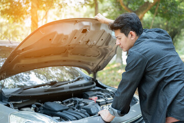 Man open car hood for repair as maintenance service. Man trying to repair a car engine, looking...