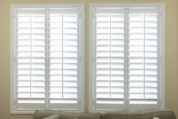 A set of open white plantation shutters in a light butter yelllow room