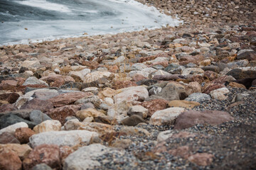Close up of the rocks at the edge of Tibble Fork Reservoir which is frozen in Salt Lake City, Utah in the month of December. 
