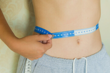 Skinny young woman measuring her waist