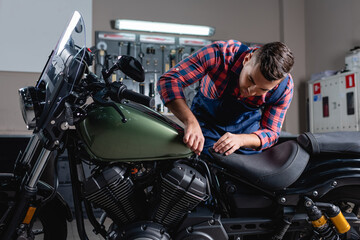 Fototapeta na wymiar repairman in overalls making diagnostics of motorbike in workshop
