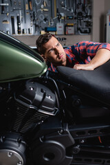 Fototapeta na wymiar young mechanic making diagnostics of motorbike in garage