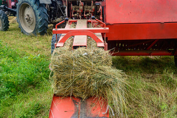 The process of harvesting hay for cattle, a tractor making bales in the field, old machinery. © Niko_Dali