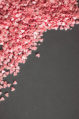 Pile of little pink heart shaped candies on the grey background. Free space for your Valentine's day greeting. Flat lay.