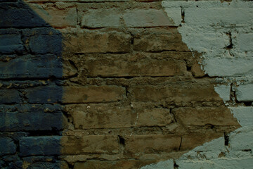 Background texture of a brick wall with painted blue and white angular pattern on exposed clay brickwork in a full frame view
