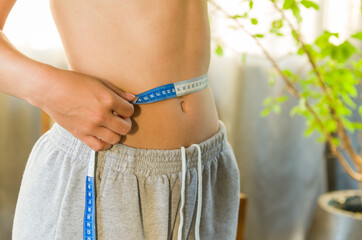 Skinny young woman measuring her waist