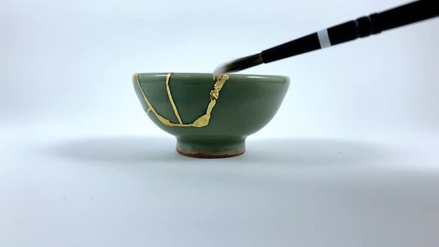 Artisan working on kintsugi process. Slow motion cinematic Kintsukuroi video. Applying gold phase.