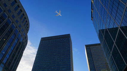 Fototapeta na wymiar Looking up passing airplane at high altitude above London city skyline, financial distrtict, United Kingdom