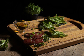 fish fillet with herbs and vegetable oil on a wooden board in a beam of light