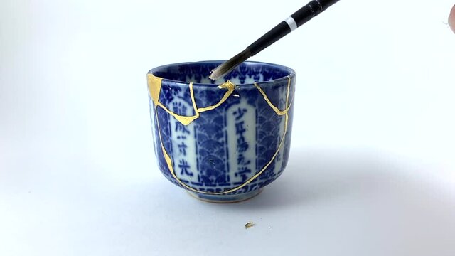 Artisan working on kintsugi process. Slow motion cinematic Kintsukuroi video. Applying gold phase.