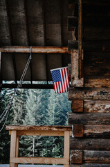 American Flag Hanging Outside An Old Homestead Cabin In The Woods
