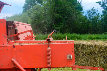 The tractor collects dry hay in the field, the hay presses the bale press, work in the field.