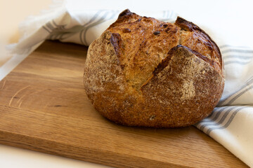 Loaf of bread wrapped in white linen towel lying on a wooden table