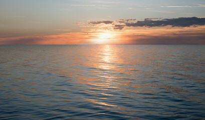 Fototapeta premium dreamy sunset scenery with sinking sun over the ocean and water reflection