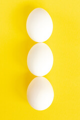 Close-up view of raw chicken eggs on yellow background.