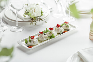 Fresh burata cheese with tomatoes and herbs on white plate