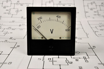 An old voltmeter on paper electrical diagrams.