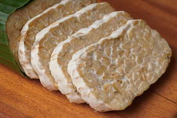 tempeh wrapped in banana leaves and tempeh slices on a wooden cutting board