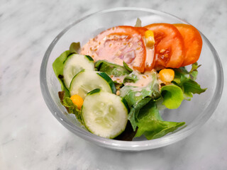 Fresh vegetable salad (lettuce, corn, cucumber, tomato) with roasted sesame Japanese dressing in glass bowl