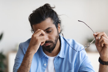 Exhausted Young Arab Man Taking Off Glasses, Feeling Eyes Fatigue