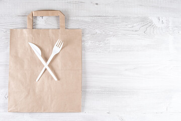 plastic fork, knife on paper bag. Eco-friendly food packaging and cotton eco bags on gray background with copy space. Carering of nature and recycling concept. containers for catering and street fast