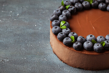 Chocolate brown cheesecake with fresh blueberries on vintage concrete background.