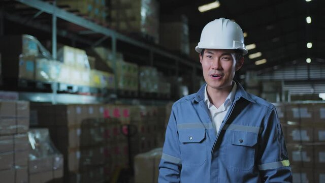 portrait of asian male professional enginner wearing uniform hardhat standing and smile with confident and cheerful in warehouse factory
