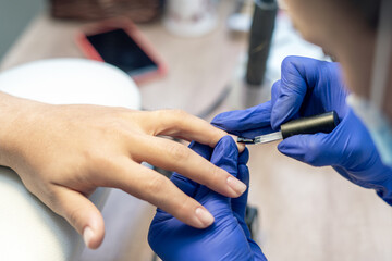 Obraz na płótnie Canvas Manicurist doing a manicure in a nail salon, applying varnish on nails