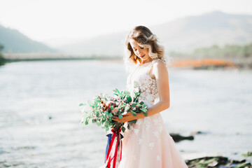 Fototapeta na wymiar Beautiful fashion bride in wedding dress posing near river