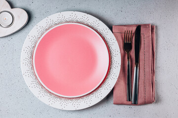  Empty pink plate, cutlery and heart shaped candle top view. Saint Valentine's day table setting