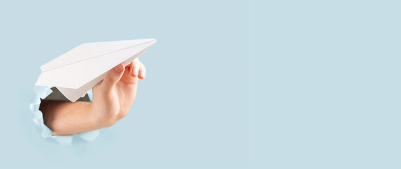 The hand launches a paper origami plane into the sky. End of quarantine concept. Banner