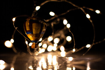 Wooden hot air balloon flying and entangled in Christmas lights.