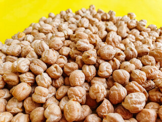 beans. Uncooked dried chickpeas on yellow background. Heap of legume chickpeas background 